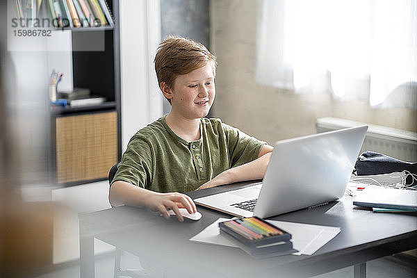 Junge während des Hausunterrichts mit Laptop zu Hause