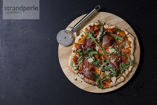 Studioaufnahme von hausgemachter Pizza mit Mozzarella  Schinken  Rucola und Parmesan