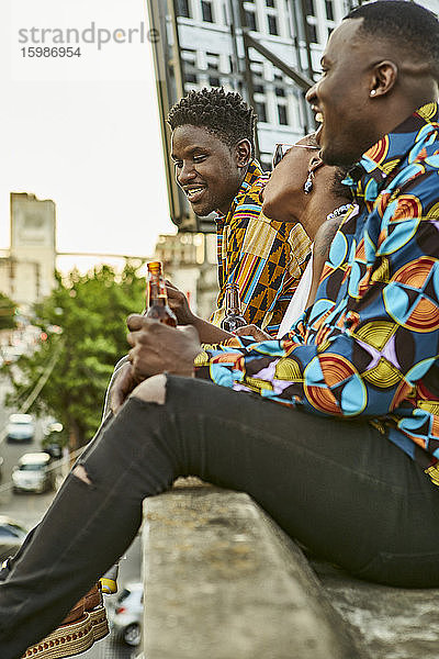 Freunde sitzen auf einer Dachterrasse in der Stadt und trinken Bier  Maputo  Mosambik