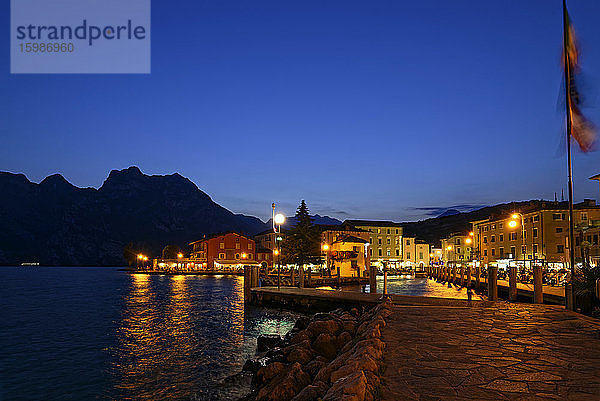 Italien  Trentino  Torbole  Gardasee  Promenade und Stadt in der Abenddämmerung beleuchtet