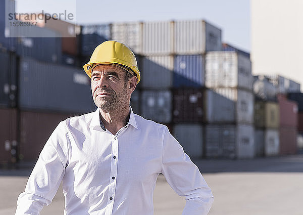 Porträt eines Geschäftsmannes mit Schutzhelm vor einem Frachtcontainer