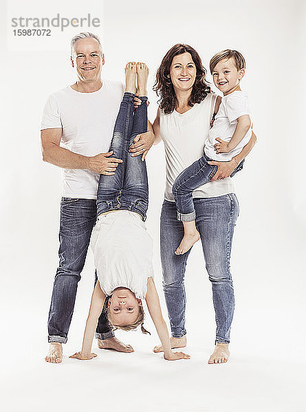 Porträt einer glücklichen Familie mit zwei Kindern  die vor einem weißen Hintergrund stehen