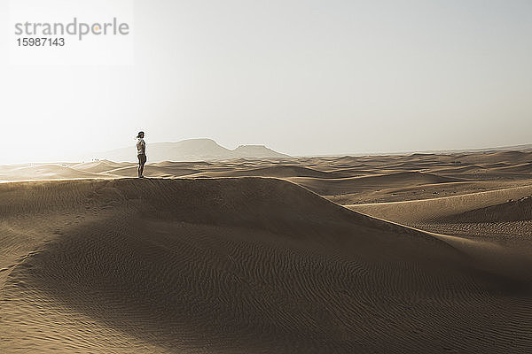 Mitteldistanz eines männlichen Touristen auf Sanddünen in der Wüste von Dubai  Vereinigte Arabische Emirate