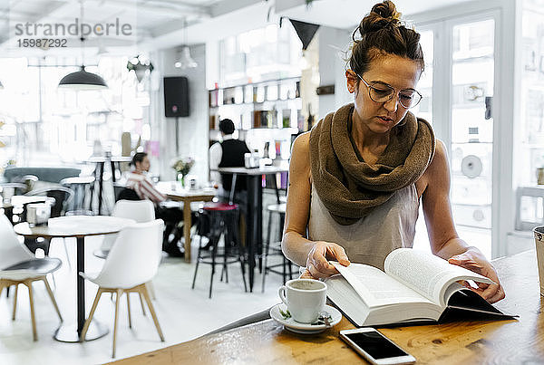 Frau liest Buch in einem Café