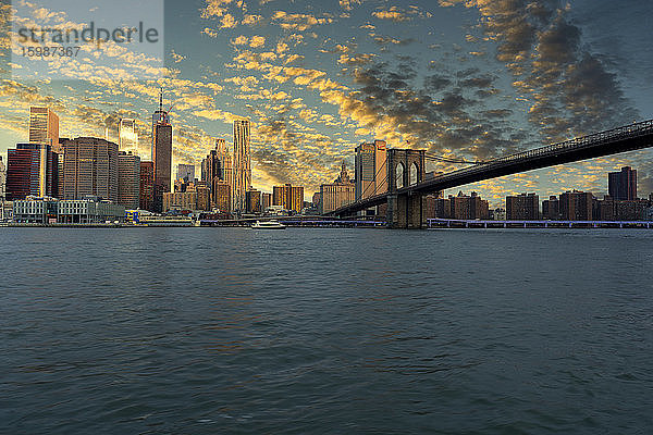 USA  New York  New York City  East River und Brooklyn Bridge bei dramatischem Sonnenaufgang mit der Skyline von Manhattan im Hintergrund