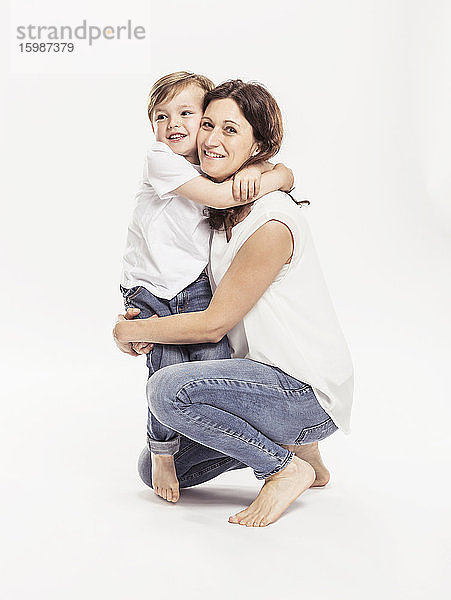 Porträt einer glücklichen Mutter und ihres kleinen Sohnes  die sich vor einem weißen Hintergrund umarmen