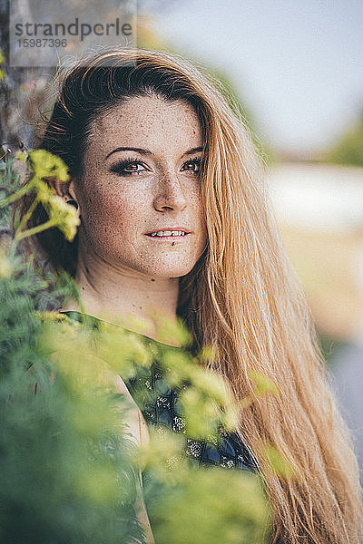 Porträt einer schönen jungen blonden Frau mit Sommersprossen im Gesicht  die im Freien steht