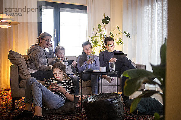 Familie nutzt drahtlose Technologien im Wohnzimmer und entspannt auf dem Sofa im modernen Zuhause