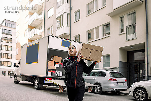 Junge Botenfrau trägt Kiste auf der Straße