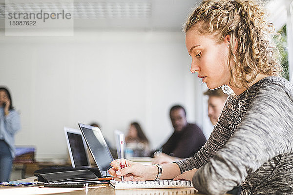 Junge Frau lernt am Schreibtisch im Klassenzimmer