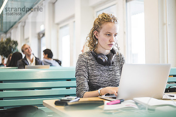 Seriöse Studentin benutzt Laptop in Cafeteria