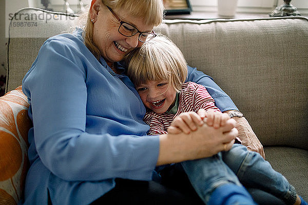 Glücklicher Junge sitzt zu Hause mit der Großmutter auf dem Sofa