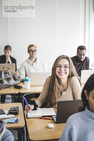 Porträt einer lächelnden jungen Frau beim Lernen im Klassenzimmer