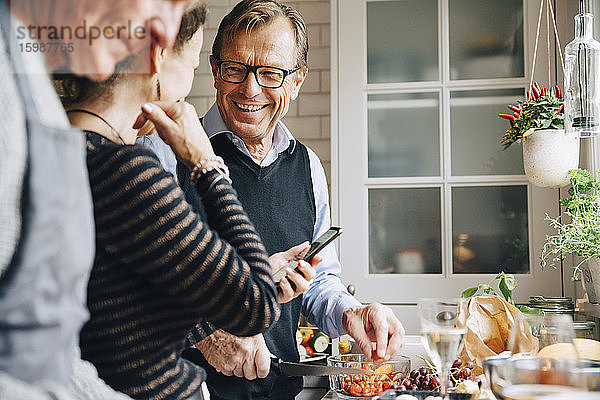 Lächelnder Mann schaut Frau an  die bei einem Freund in der Küche steht