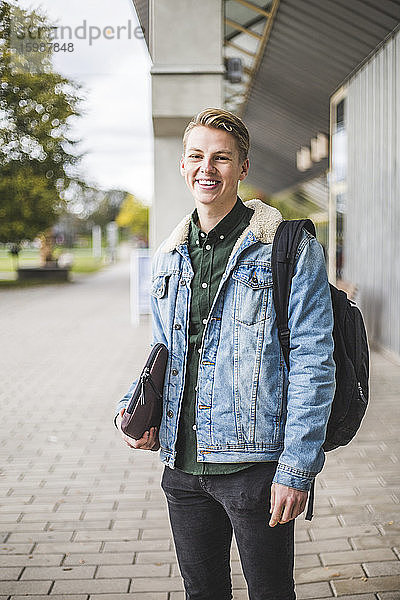 Porträt einer lächelnden jungen Frau  die auf dem Universitätscampus steht