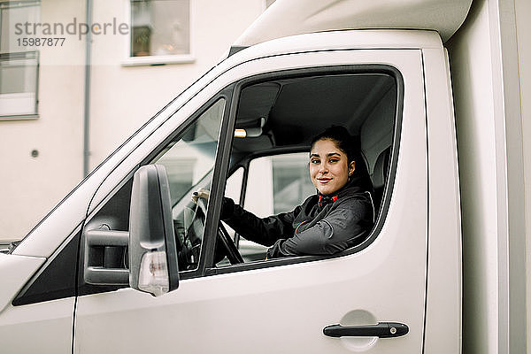 Porträt einer jungen Lieferfrau am Steuer eines Lastwagens