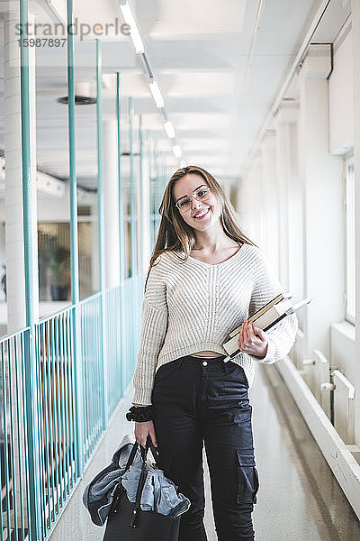 Porträt einer lächelnden jungen Studentin im Korridor der Universität