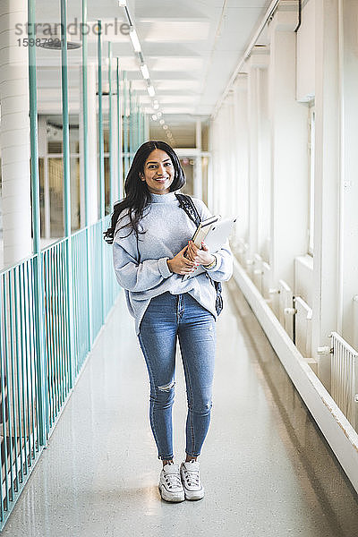 Porträt einer jungen Studentin  die im Korridor der Universität steht
