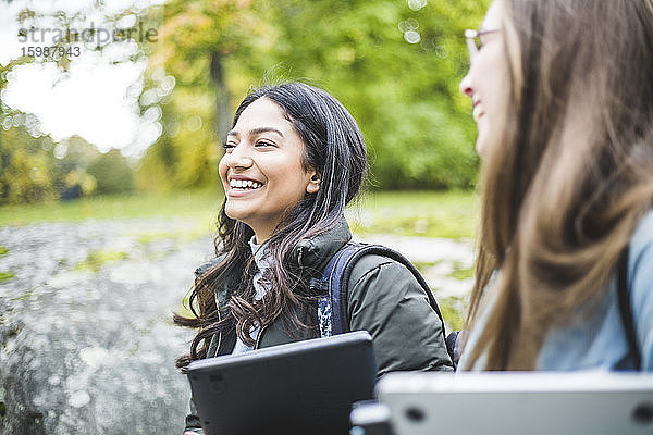 Lächelnde junge Frau mit Freundin auf dem Universitätscampus