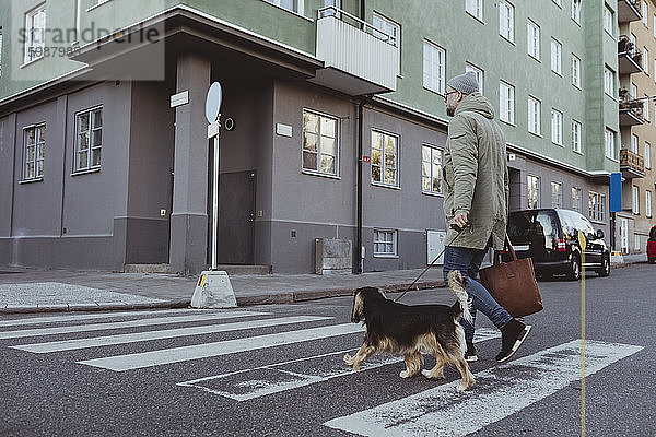 Mann in voller Länge mit Hund über die Straße in der Stadt