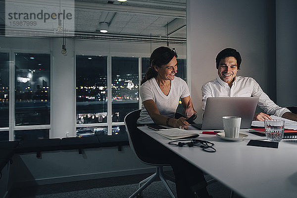 Lächelnder Geschäftsmann und Geschäftsfrau planen Strategie  während sie im Büro auf den Laptop schauen