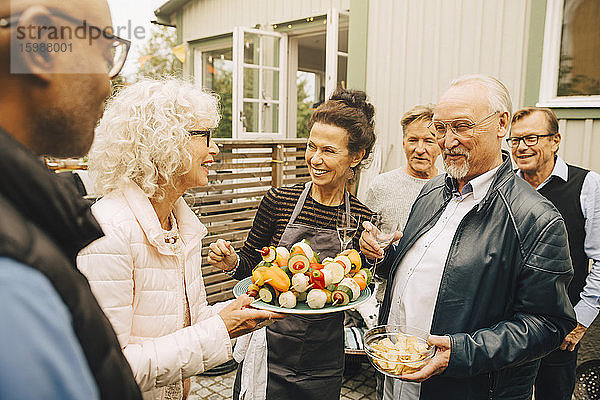 Lächelnde ältere Frauen und Männer genießen Gartenparty