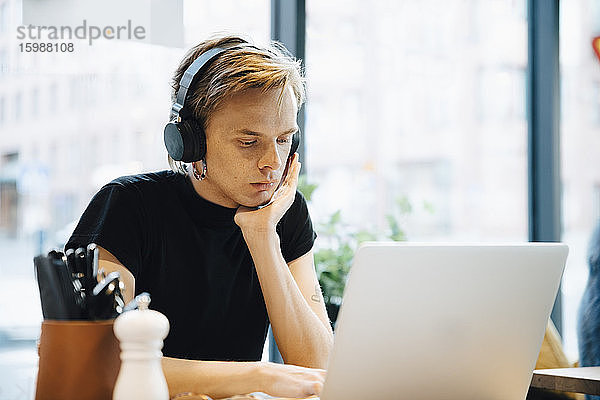 Selbstbewusste junge Transgender sitzen mit Laptop im hellen Café