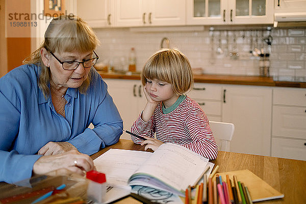 Großmutter hilft Enkel bei den Hausaufgaben zu Hause