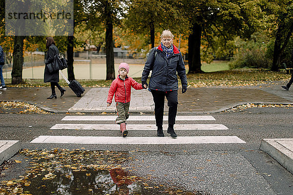 Großmutter geht mit ihrem Enkel auf einem Fußweg in der Stadt