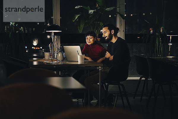 Geschäftsmann und Geschäftsfrau mit Laptop bei der späten Nachtarbeit im Büro