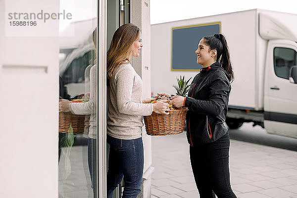 Lieferfrau liefert Früchte an reife Kundin aus