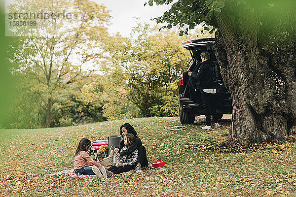 Eltern mit Töchtern genießen Picknick im Herbst