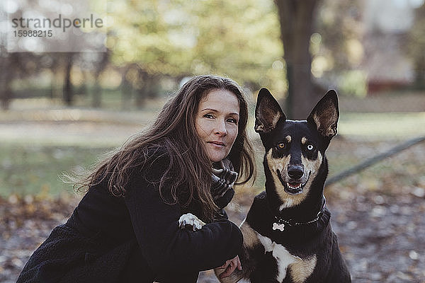 Seitenansicht Porträt einer lächelnden Frau mit Hund im Park
