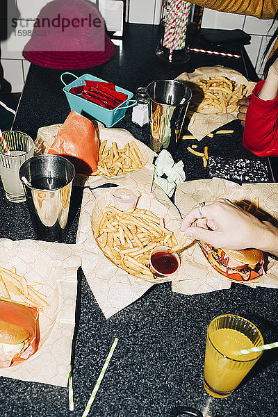 Schrägaufnahme von Freunden  die Pommes Frites am Tisch im Café essen