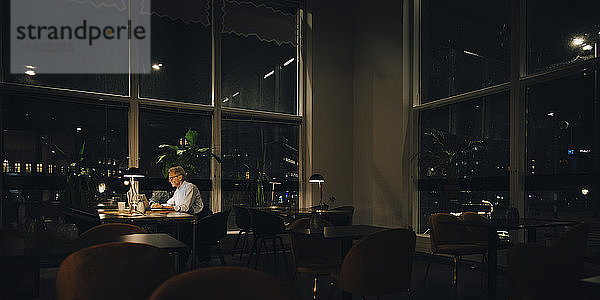 Entschlossener leitender Geschäftsmann  der spät nachts in einem dunklen Büro arbeitet