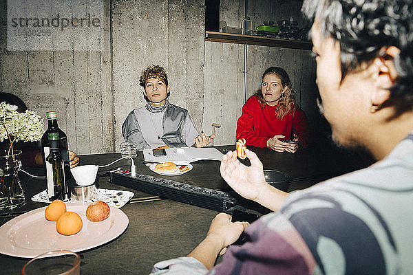 Männlicher Unternehmer im Gespräch mit Kollegen am Tisch im Kreativbüro