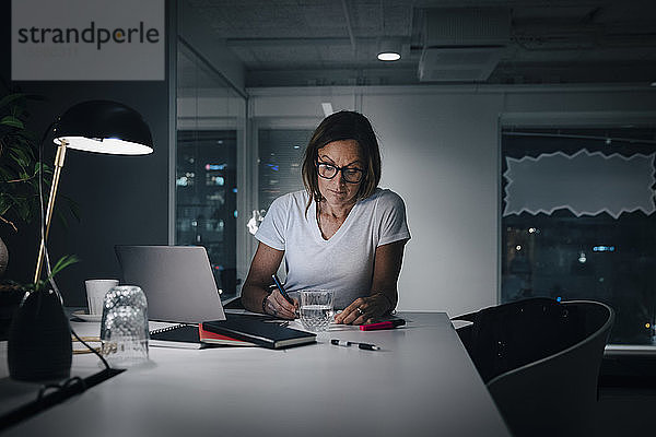 Weibliche Berufstätige  die spät arbeiten  während sie im Büro am Schreibtisch sitzen