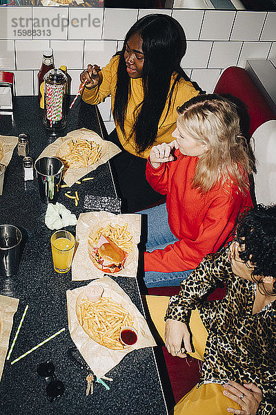 Schrägansicht auf männliche und weibliche Freunde beim Essen am Tisch im Café