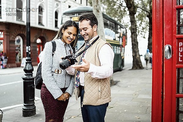 Glückliches reisendes Ehepaar beim Betrachten von Fotos auf ihrer Kamera  London  Großbritannien  Europa