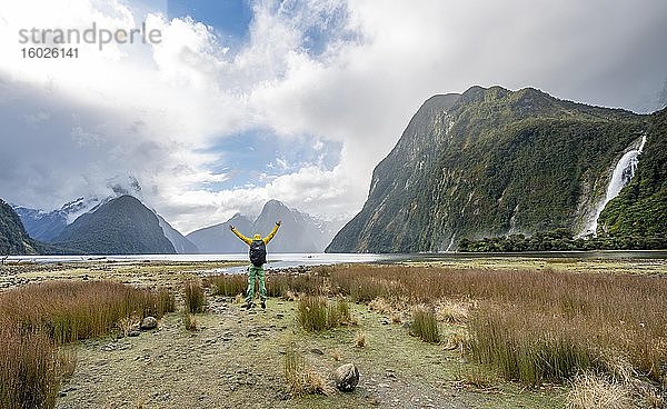 Junger Mann springt in die Luft  Mitre Peak  Bow Falls  Milford Sound  Fiordland Nationalpark  Te Anau  Southland  Südinsel  Neuseeland  Ozeanien