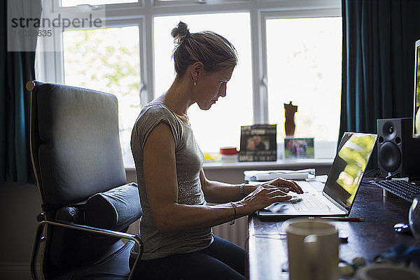 Frau  die von zu Hause aus am Laptop im Home-Office arbeitet