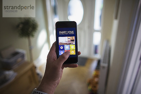 POV Mann greift über Smartphone auf Hausautomatisierung zu
