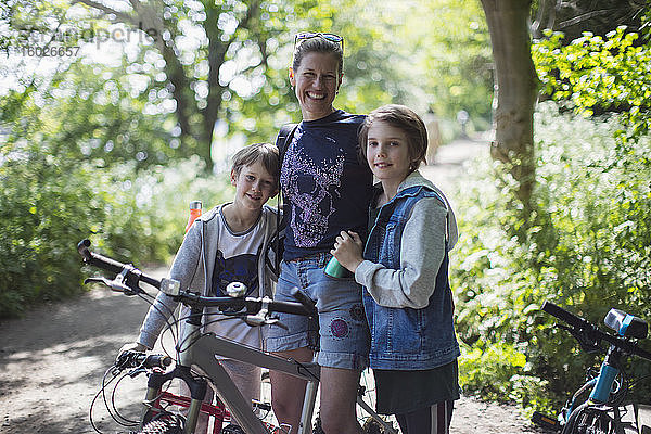 Porträt einer glücklichen Mutter und ihrer Söhne beim Radfahren in einem sonnigen Park