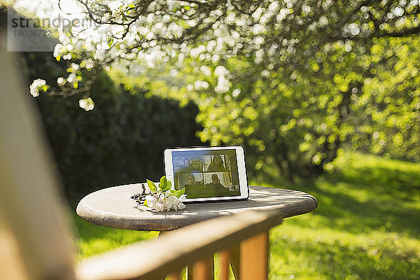 Video-Chat mit Freunden auf digitalem Tablet-Bildschirm im sonnigen Garten