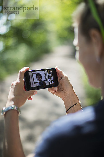 Frau im Video-Chat mit Freunden auf dem Bildschirm eines Smartphones