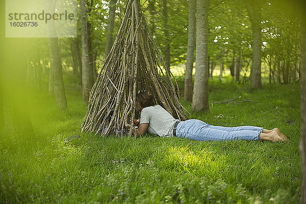 Frau am Ast-Tipi im Wald liegend