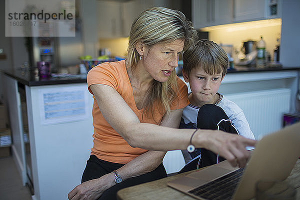 Mutter hilft Sohn bei den Hausaufgaben am Laptop