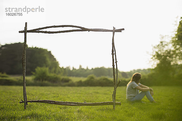 Zweigrahmen über einer Frau  die sich im Sommer im Grasfeld entspannt