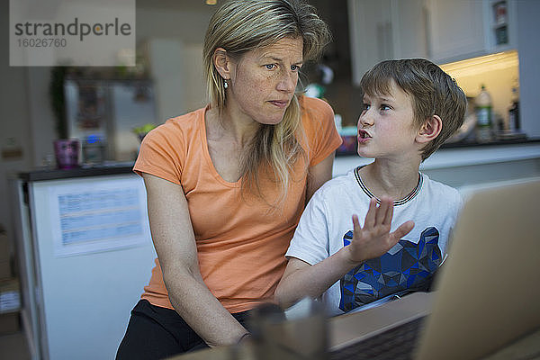 Mutter und Sohn benutzen zu Hause einen Laptop