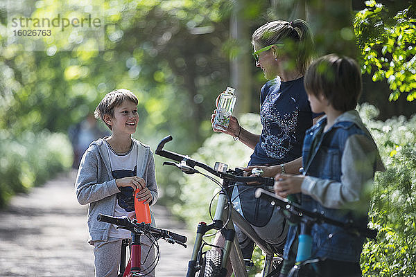 Mutter und Söhne trinken Wasser beim Radfahren